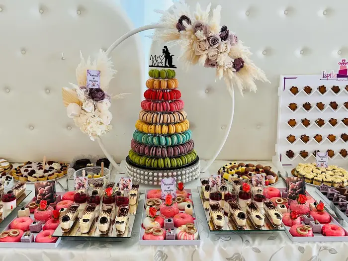 Masă de candy bar de nuntă, cu piramidă de macarons, monoporții și prăjituri asortate