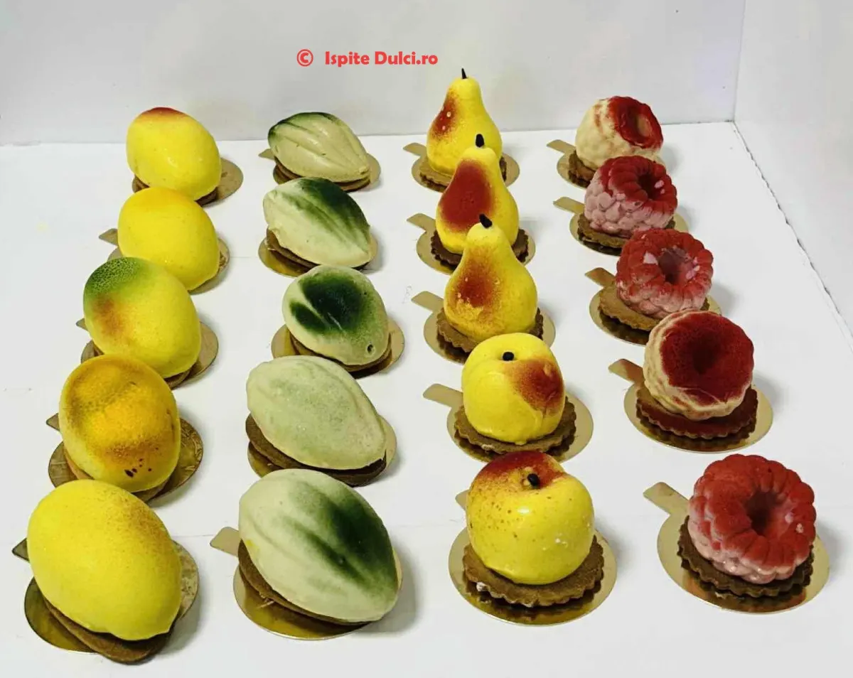 Prăjituri individuale în formă de fructe — lămâie, pară, măr și zmeură — aranjate în cutie
